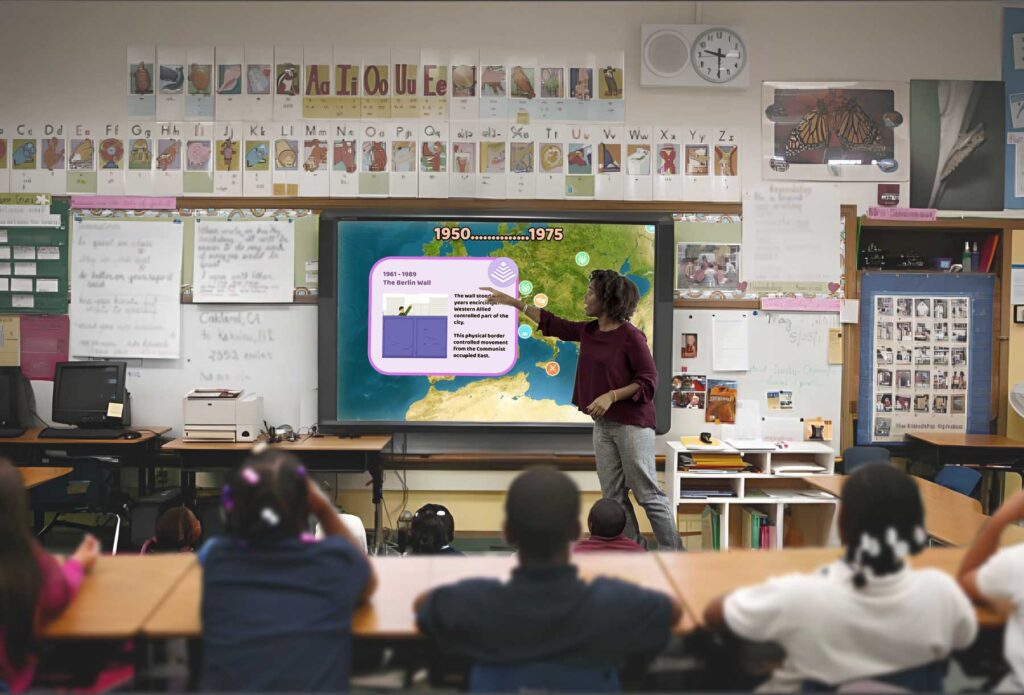 a teacher at the front of class teaching with Aeons on an interactive whiteboard